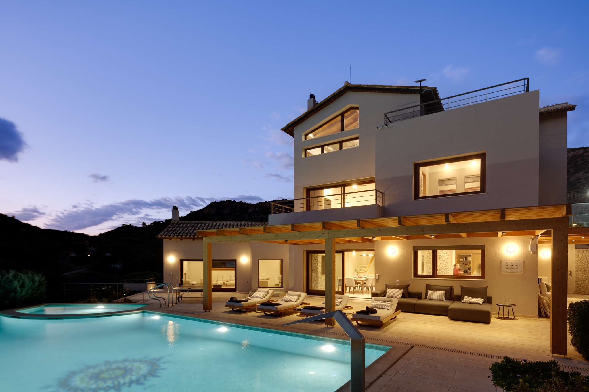 Villa Lithos at dusk: the main house, pergola terrace and heated infinity pool of this large private villa near Athens in Porto Rafti