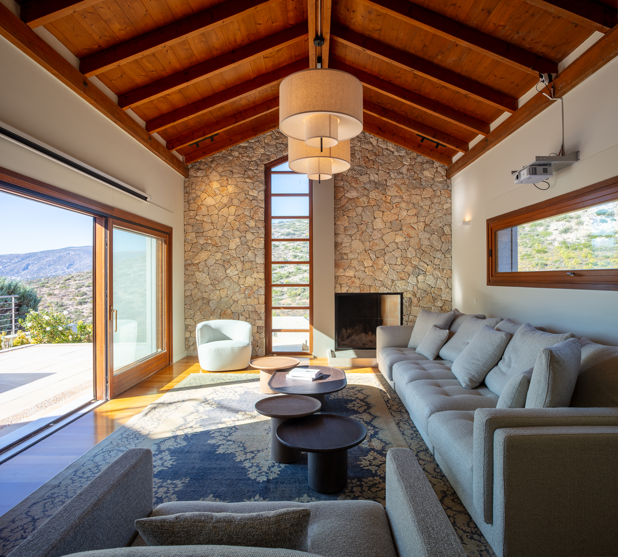 Fireplace lounge at Villa Lithos with a stone wall and wooden beamed ceiling