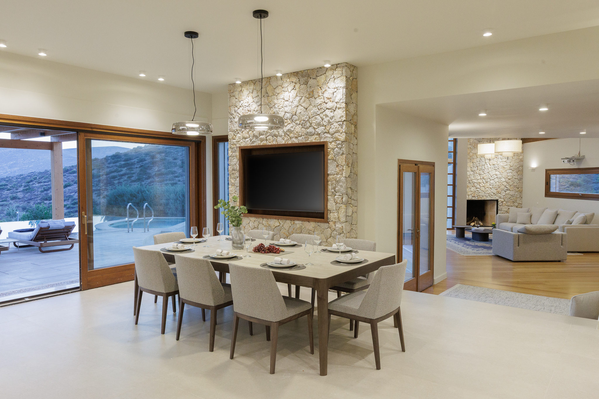 Open-plan dining and living room at Villa Lithos Porto Rafti with glass doors to the pool terrace and sea views